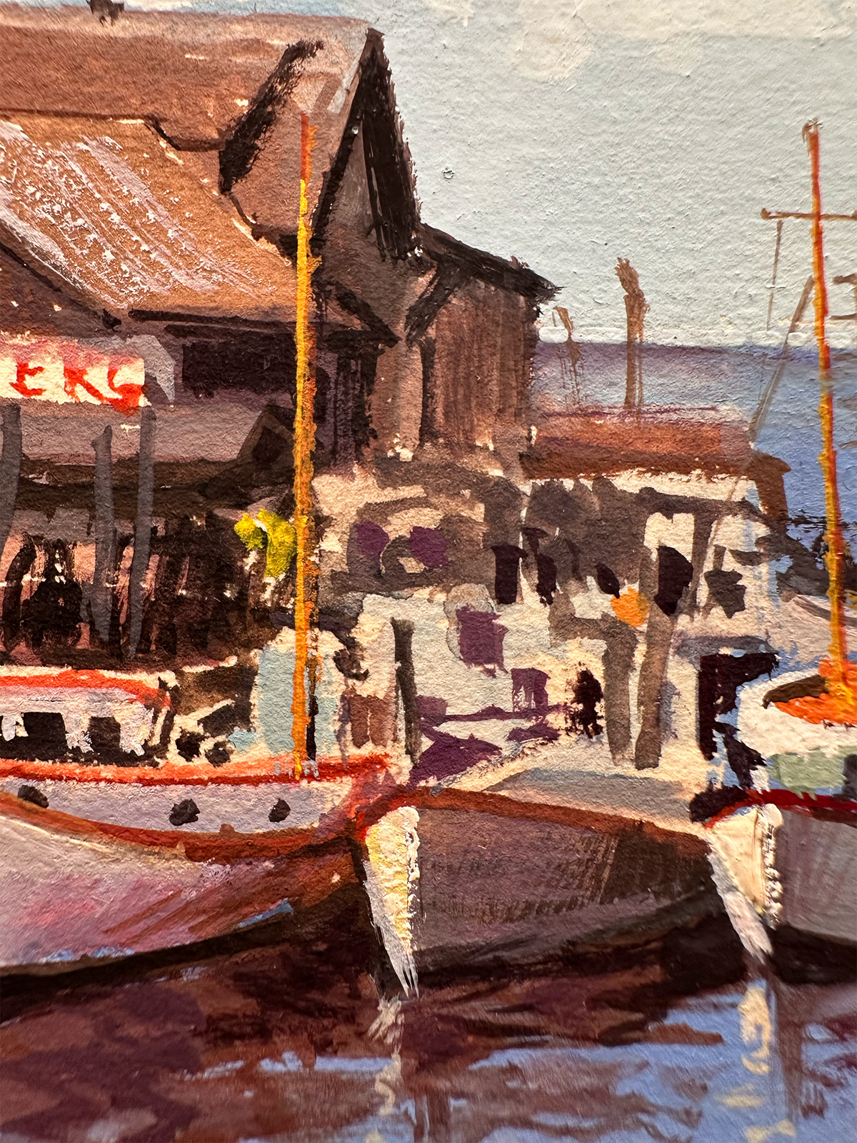 Impressionistic gouache painting of harbor boats moored in front of rustic buildings, with reflections in the water and a pale sky above.